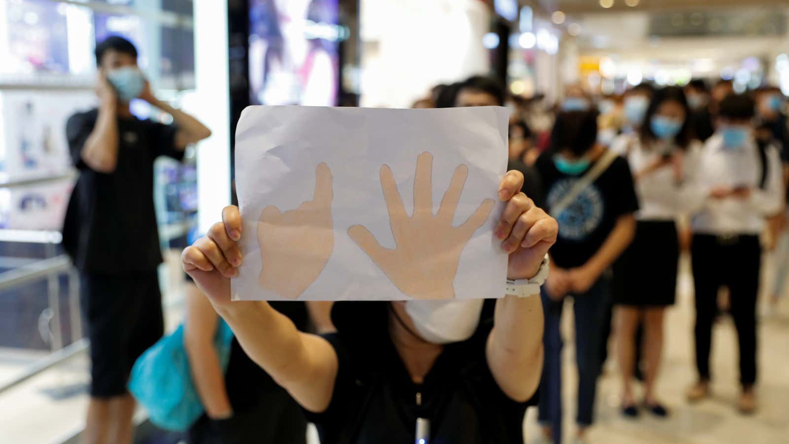 A pro-democracy demonstrator holds a paper with a symbol of “Five demands, not one less” during a protest to mark the first anniversary of an…