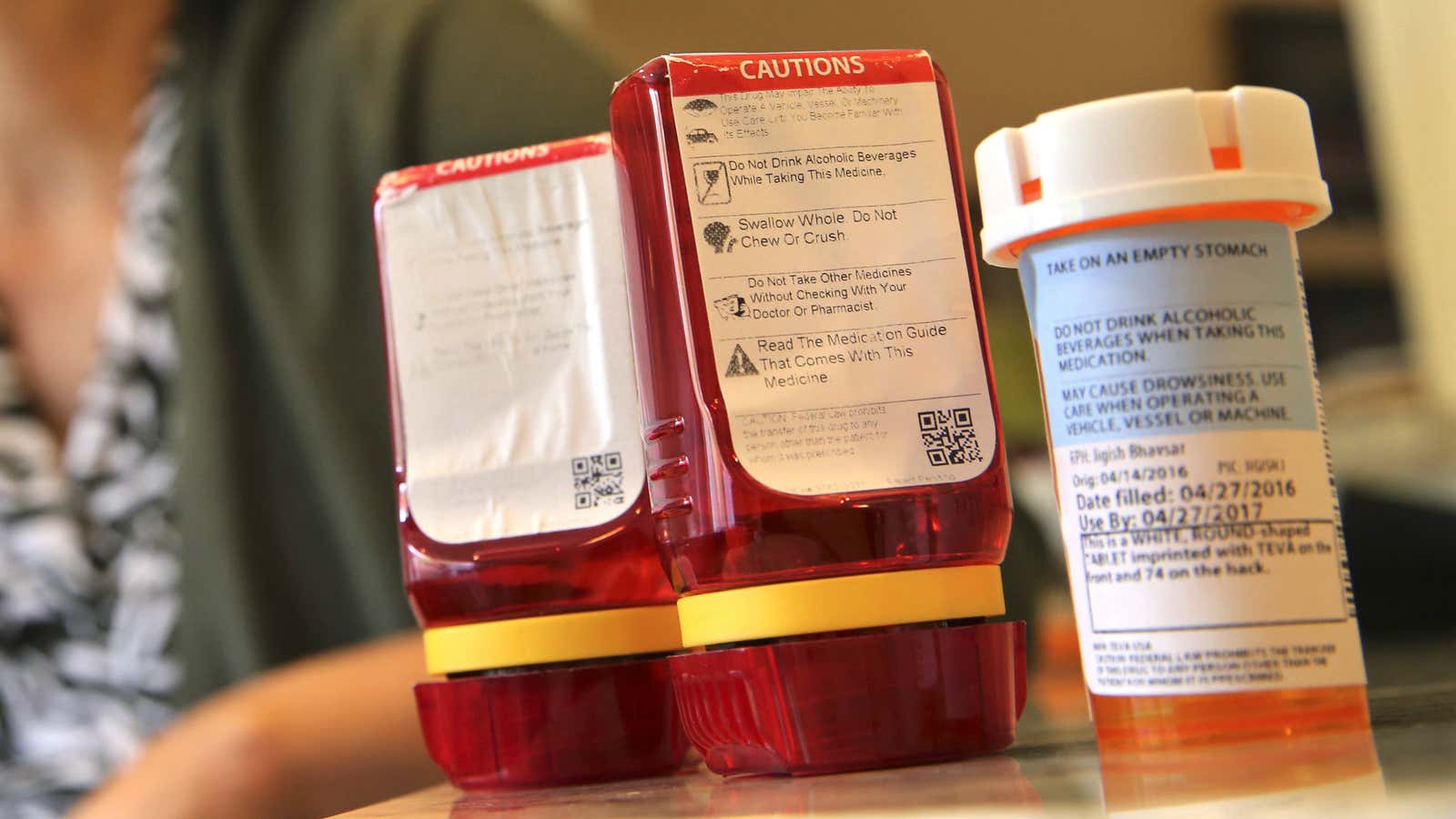 In this Sunday, Sept. 18, 2016, photo, Shelley Ewalt sits in her home, in Princeton, N.J., near an amber-colored CVS pharmacy prescription bottle, right, and…