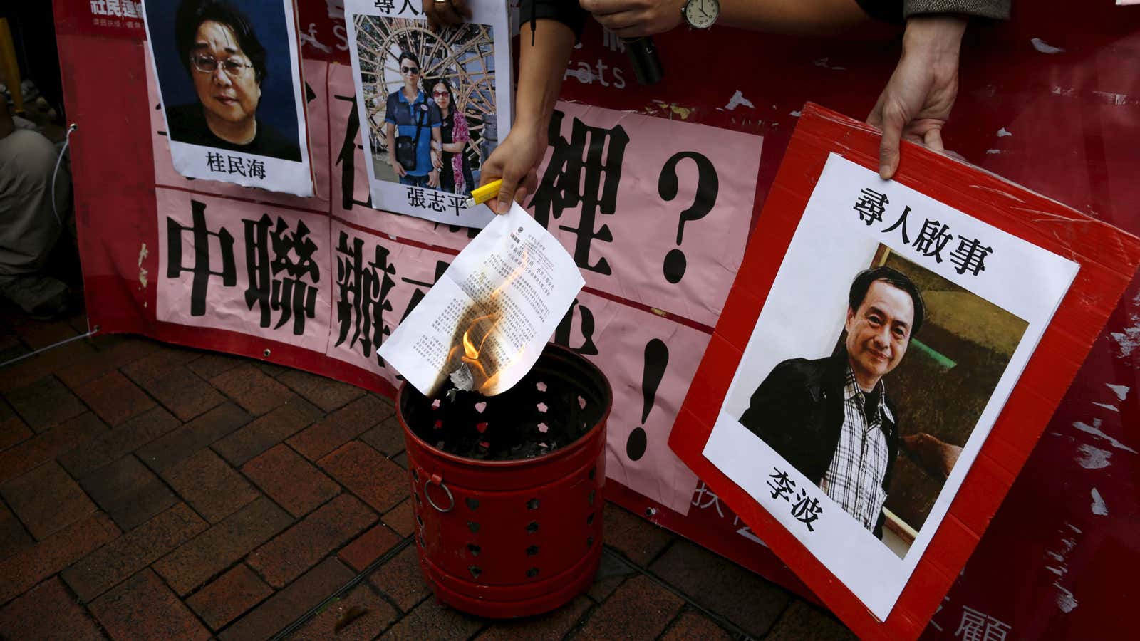 Hong Kong protesters holding search notices for the missing booksellers.