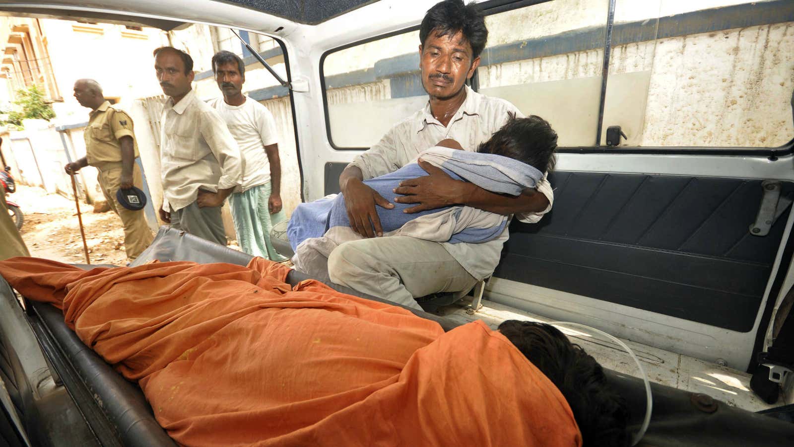 A man holds his daughter, a victim of recent food poisoning, in an ambulance.