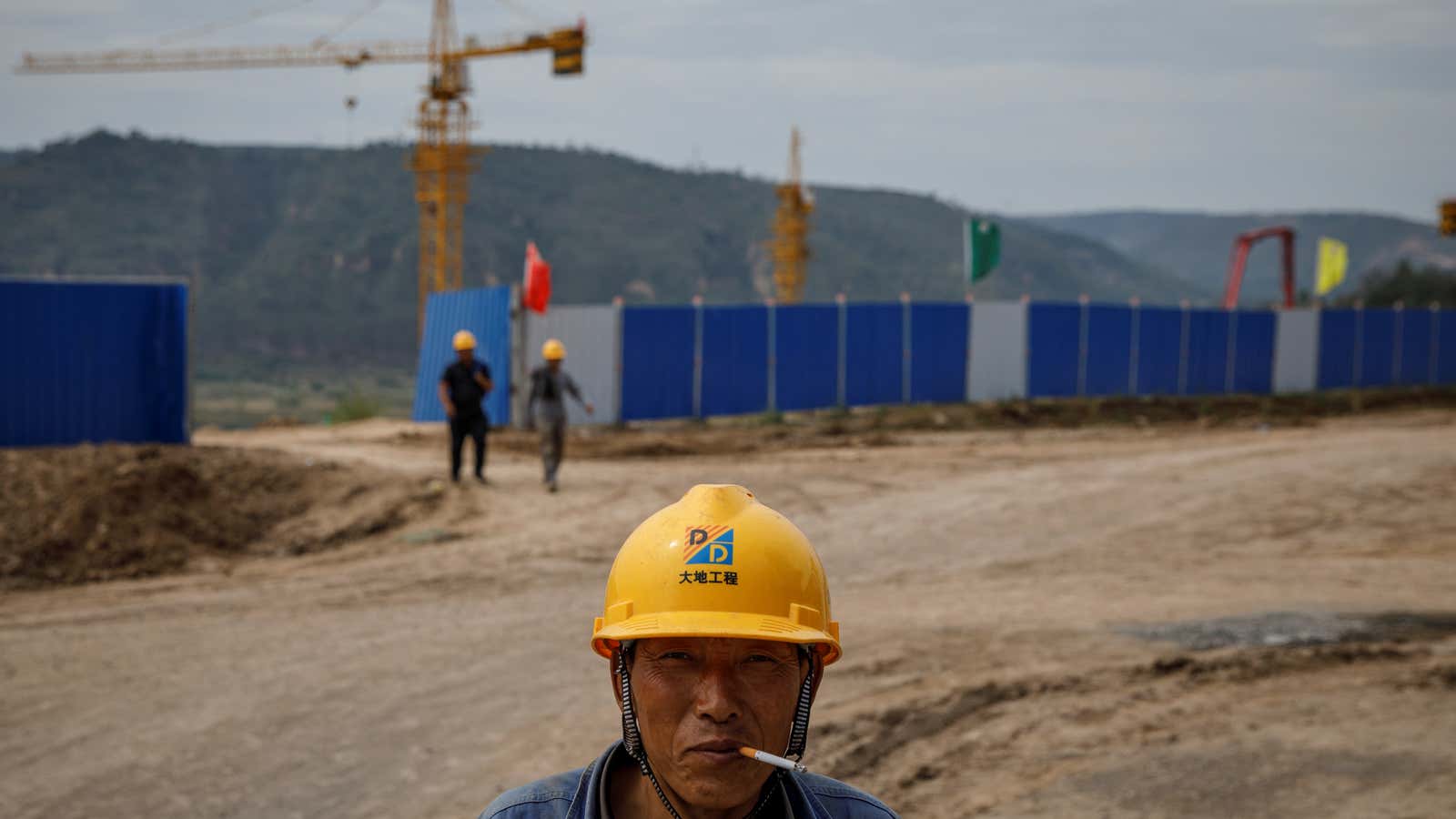 A worker stands outside a construction site of the Xinzhuang coal mine that is part of Huaneng Group’s integrated coal power project near Qingyang, Ning…