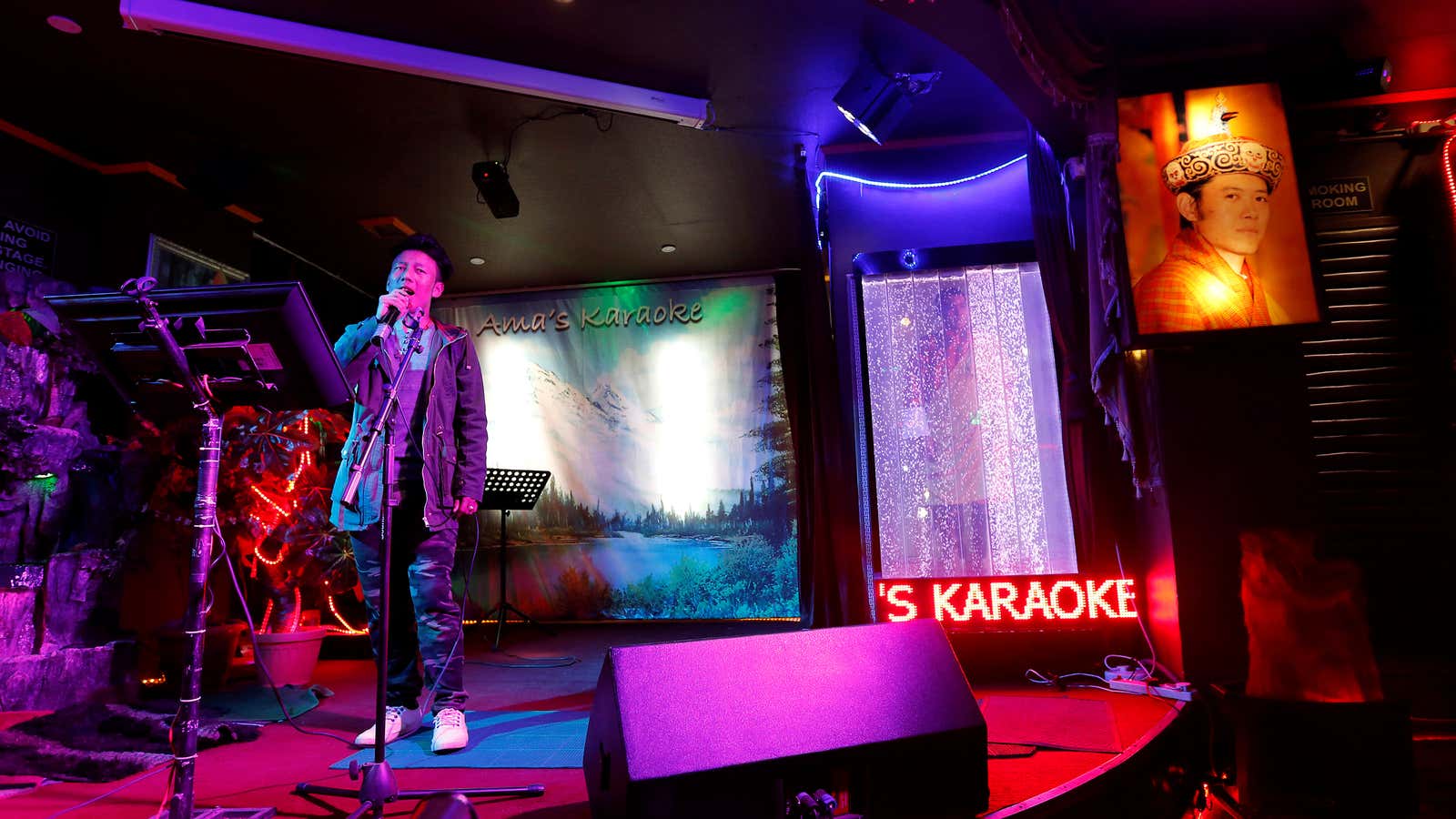 A man sings in a Karaoke bar beside a portrait of King Jigme Khesar Namgyel Wangchuck in the capital city of Thimphu, Bhutan, December 16, 2017. REUTERS/Cathal McNaughton         SEARCH “BHUTAN” FOR THIS STORY. SEARCH “WIDER IMAGE” FOR ALL STORIES.