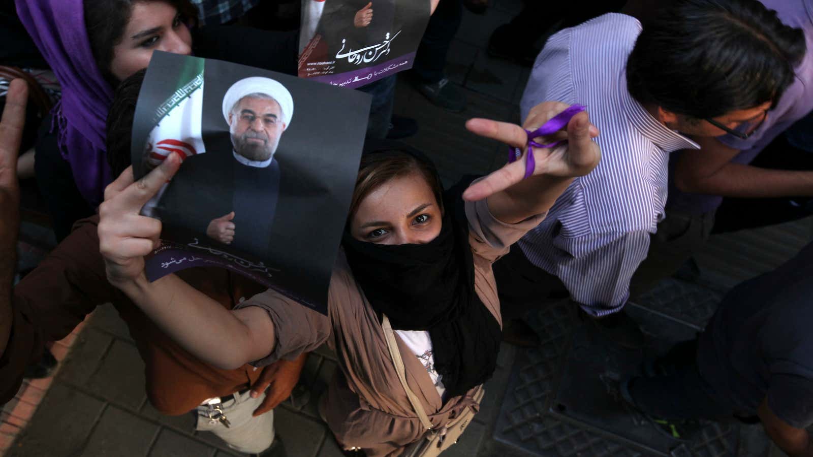 A female supporter of Iranian presidential candidate Hasan Rowhani, flashes a victory sign as she holds his poster during a celebration gathering in Tehran, Iran,…