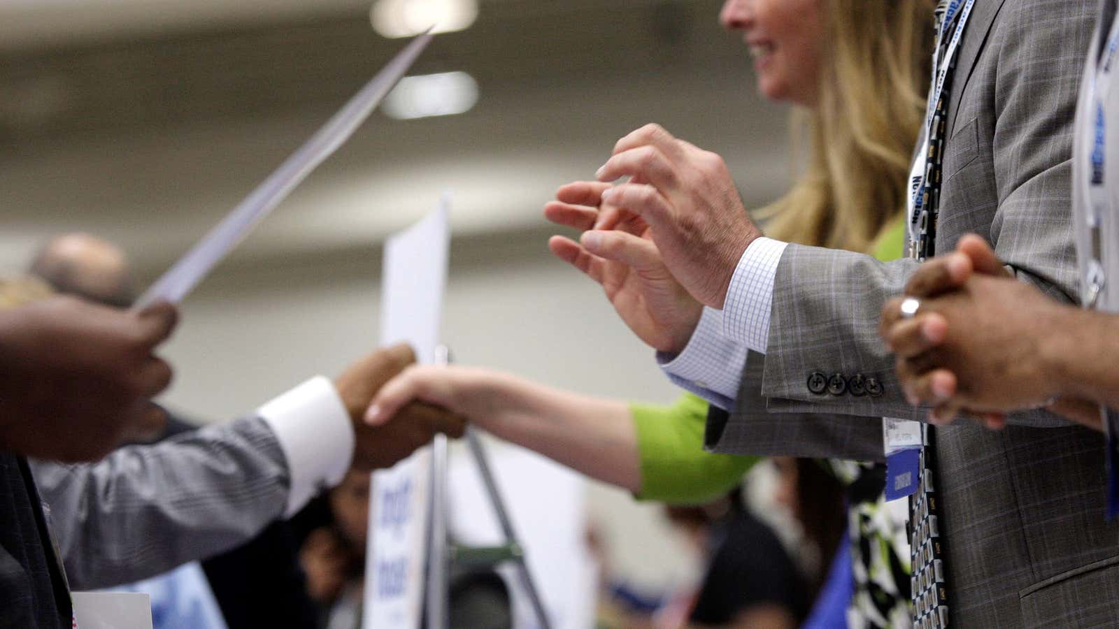 Corporate recruiters (R) gesture and shake hands as they talk with job seekers at a Hire Our Heroes job fair targeting unemployed military veterans and…