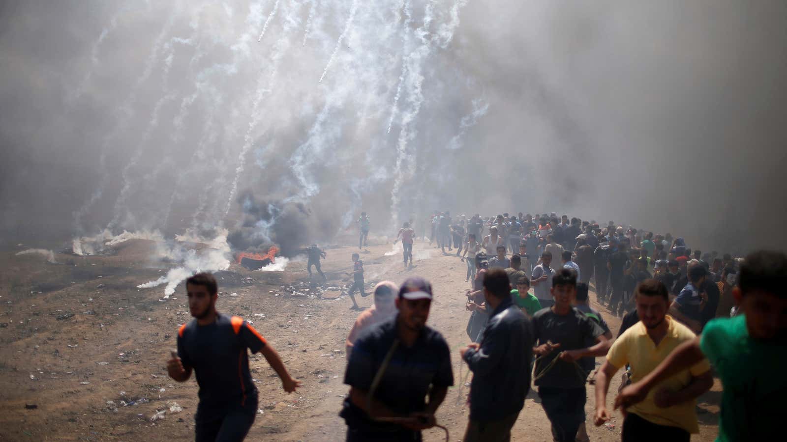 Palestinian demonstrators run from tear gas fired by Israeli troops.