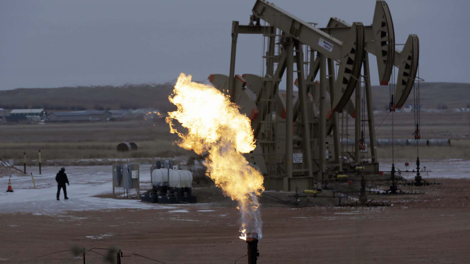 Workers tend to oil pump jacks behind a natural gas flare near Watford City, N.D. Oil pumps can be a major source of methane leaks.