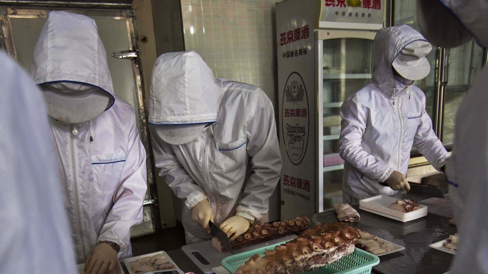 North Korean workers slice up pieces of octopus at a seafood factory inside the Rason Special Economic Zone.