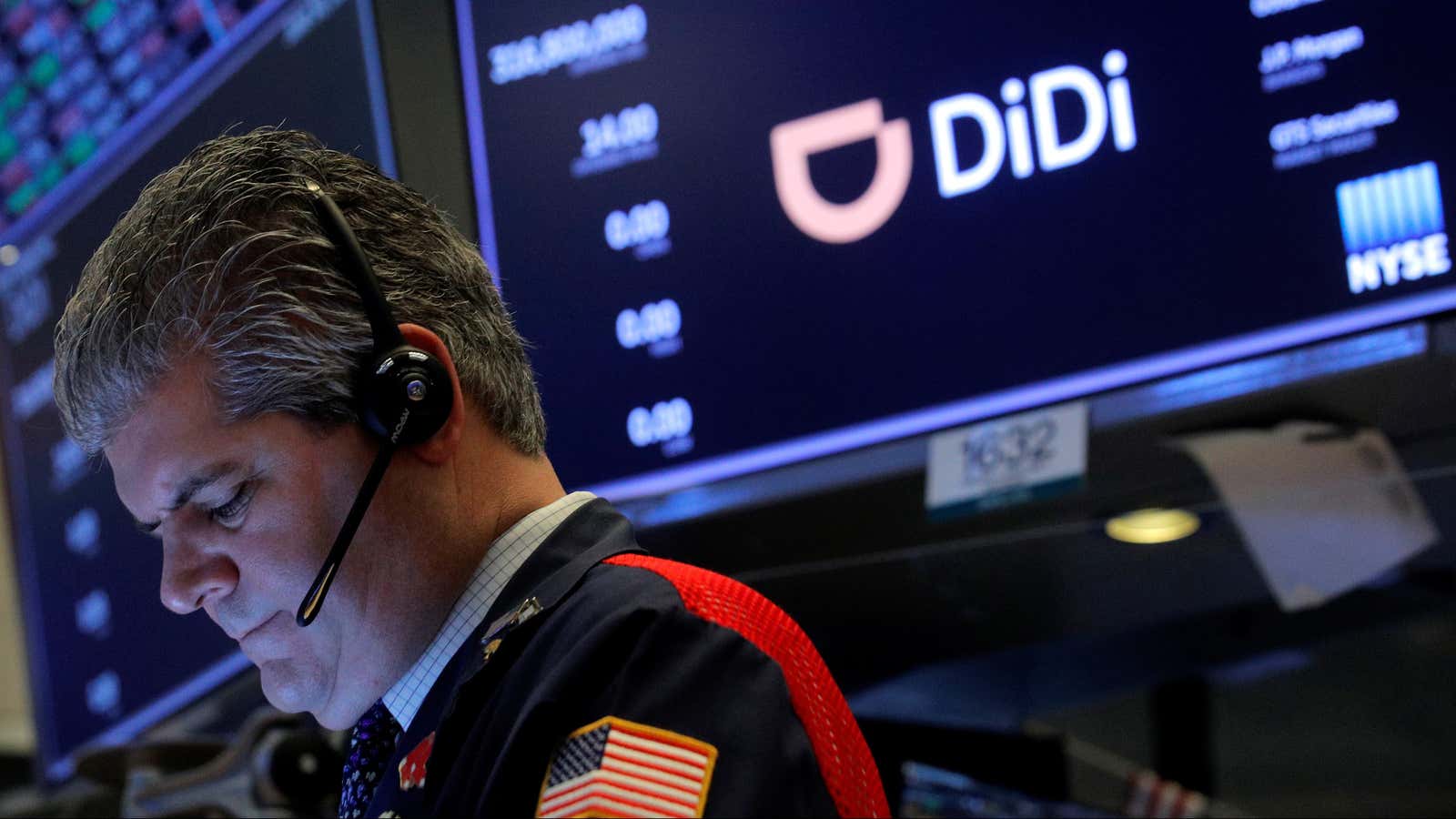 A stock trader with a US flag emblazoned on his sleeve works in front of a screen displaying the logo for Chinese ride-hailing app Didi…