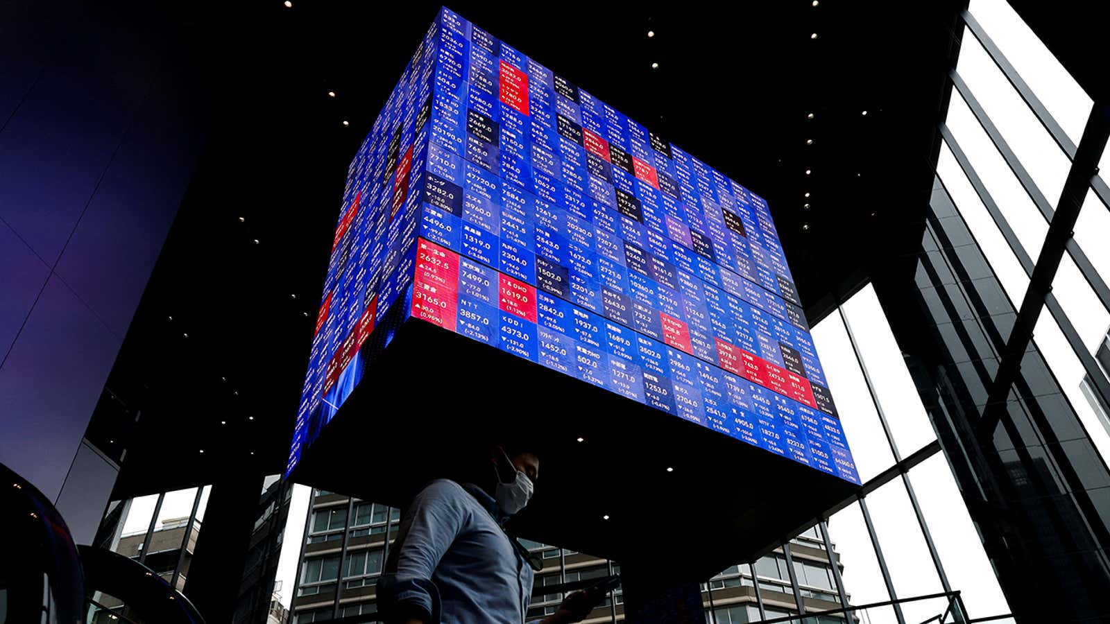 A man walks under an electronic screen showing Japan’s Nikkei share price index inside a conference hall in Tokyo, Japan June 14, 2022. REUTERS/Issei Kato