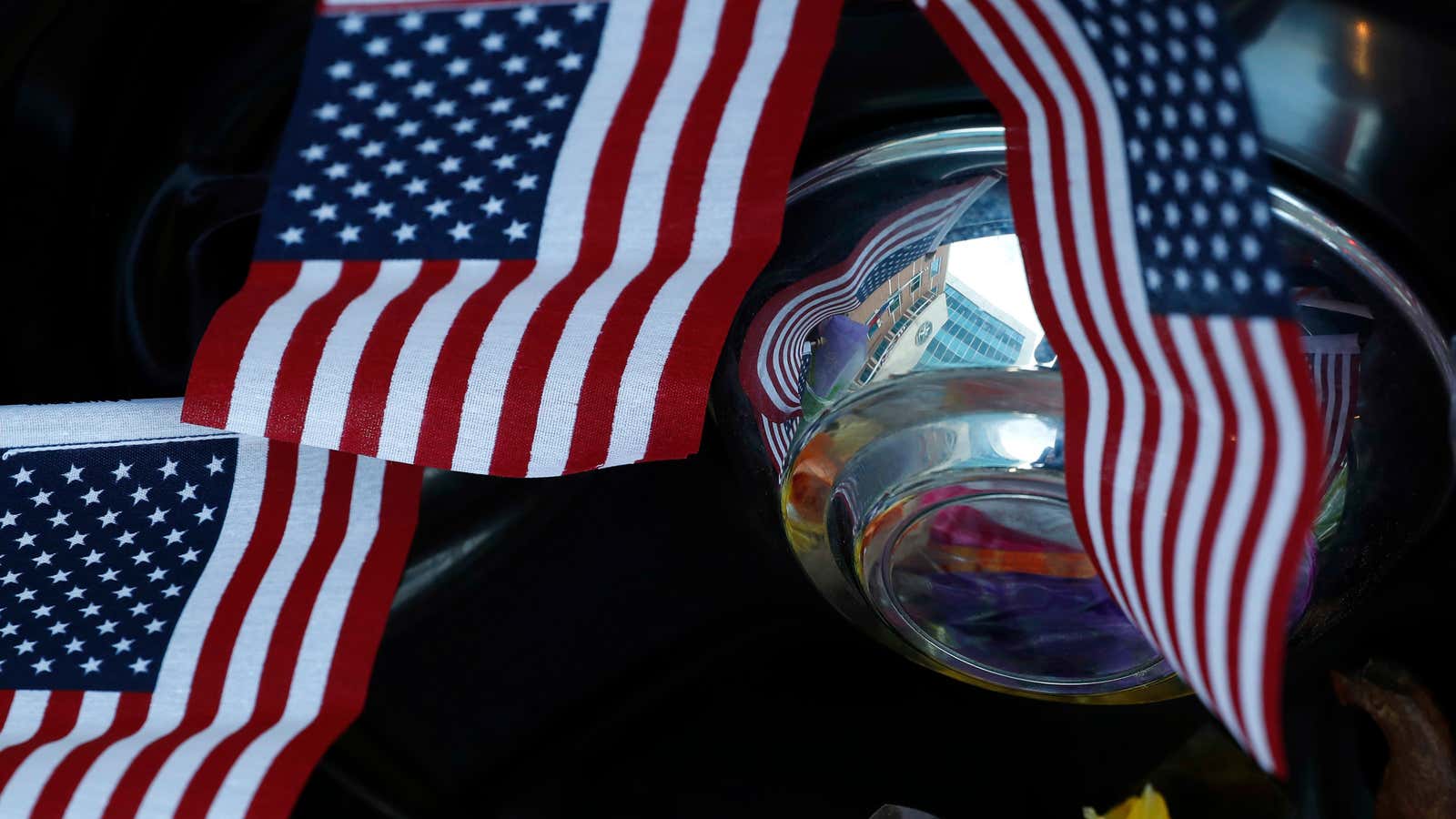 The Dallas Police Department headquarters building is reflected in the hubcap of a police car that is part of a makeshift memorial, Sunday, July 10, 2016, in Dallas. Five police officers were killed and several injured during a shooting in downtown Dallas Thursday night. (AP Photo/Eric Gay)