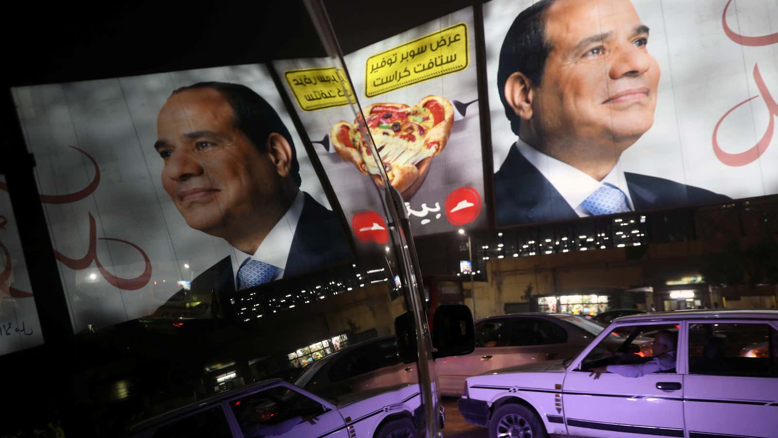 People walk in front of banners with Egypt’s President Abdel Fattah al-Sisi during preparations for the presidential election in Cairo, Egypt, March 25, 2018.