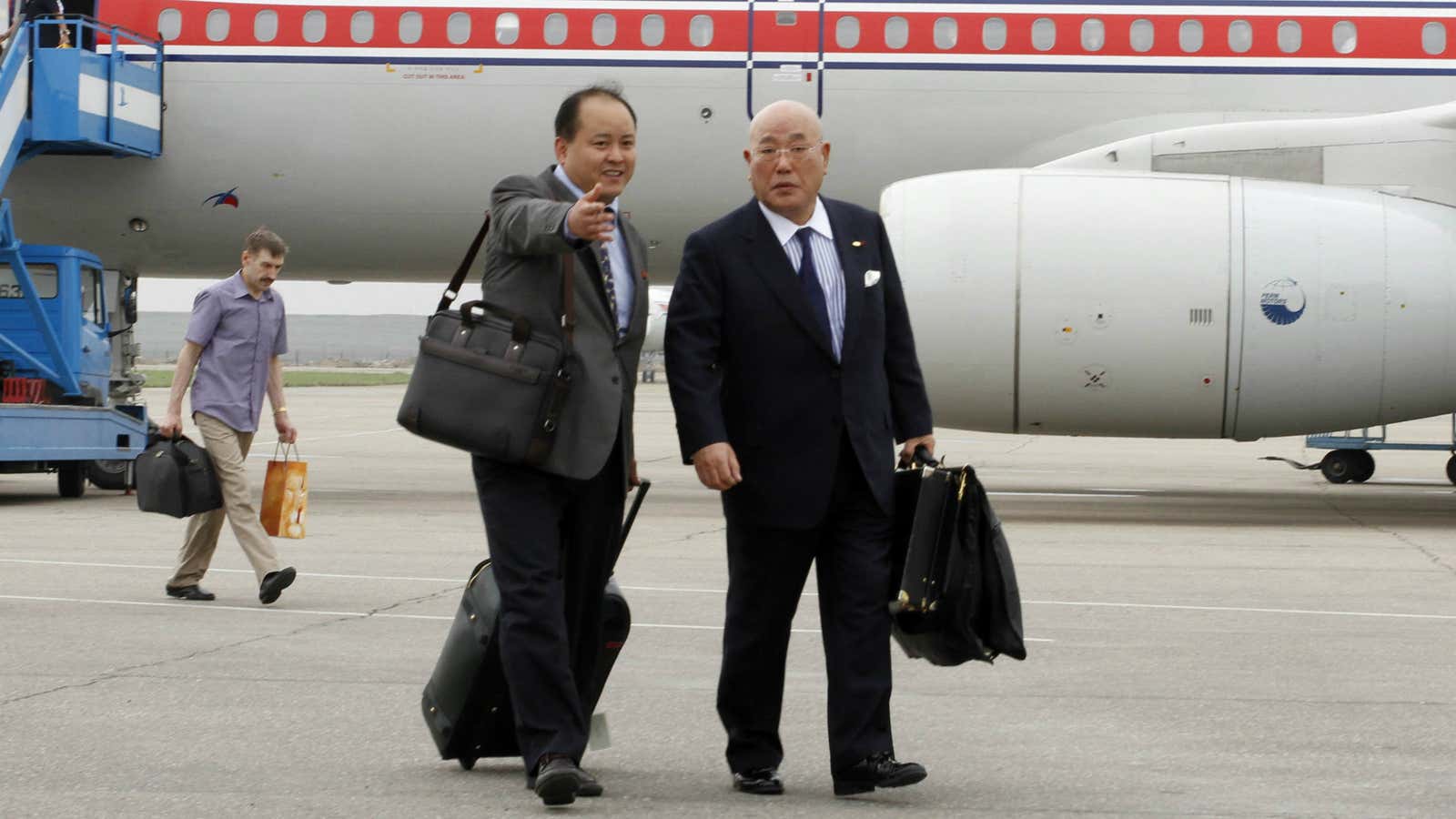 Isao Iijima, right, arrives at Pyongyang airport on Tuesday.