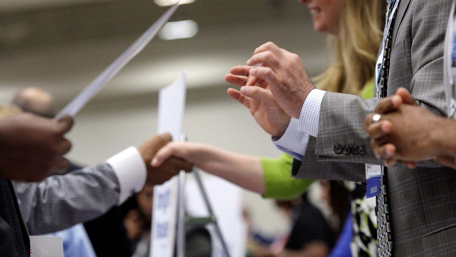 Corporate recruiters (R) gesture and shake hands as they talk with job seekers at a Hire Our Heroes job fair targeting unemployed military veterans and…