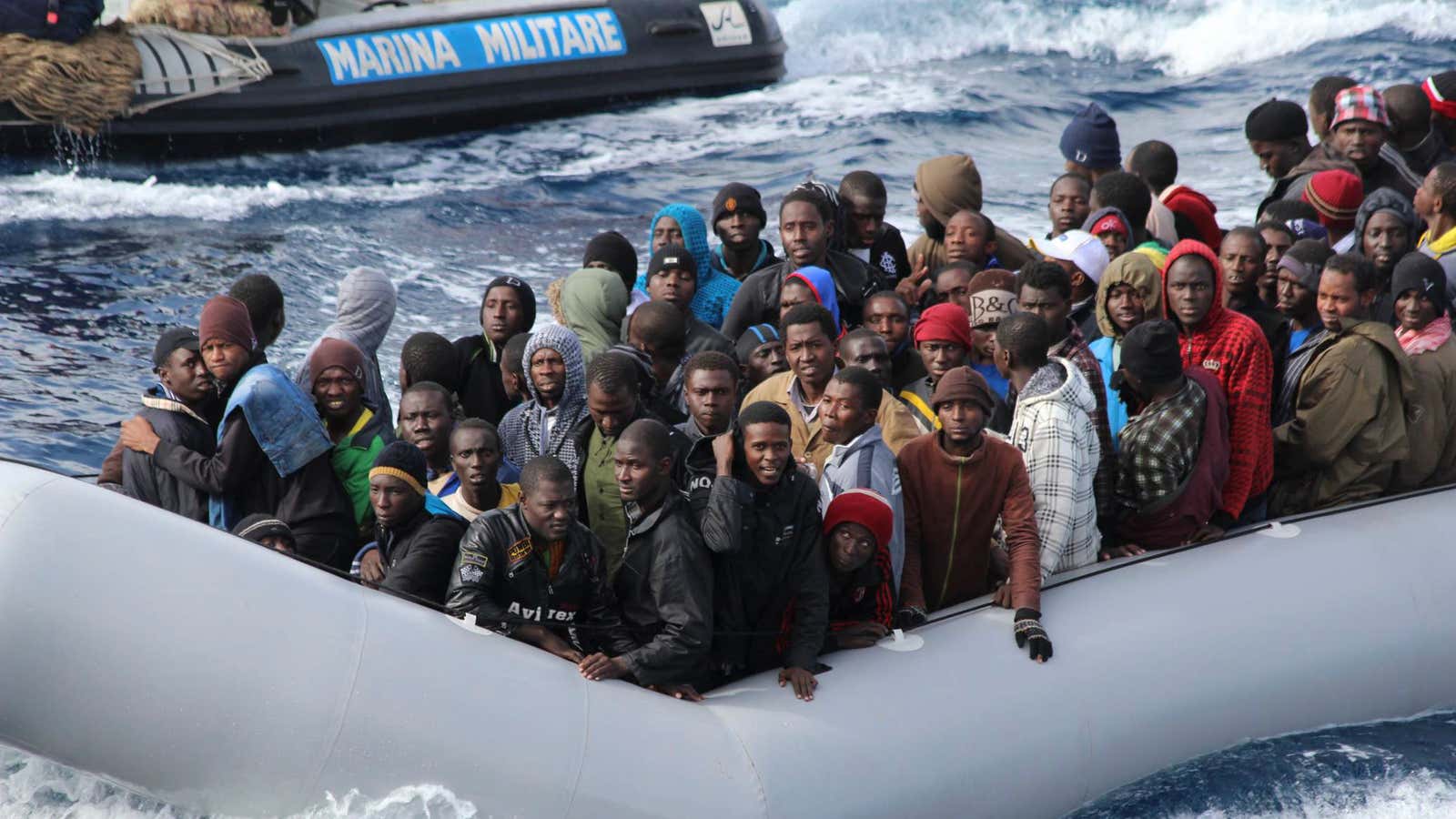 Migrants sit in a boat during a rescue operation by Italian navy off the coast of the south of the Italian island of Sicily in…