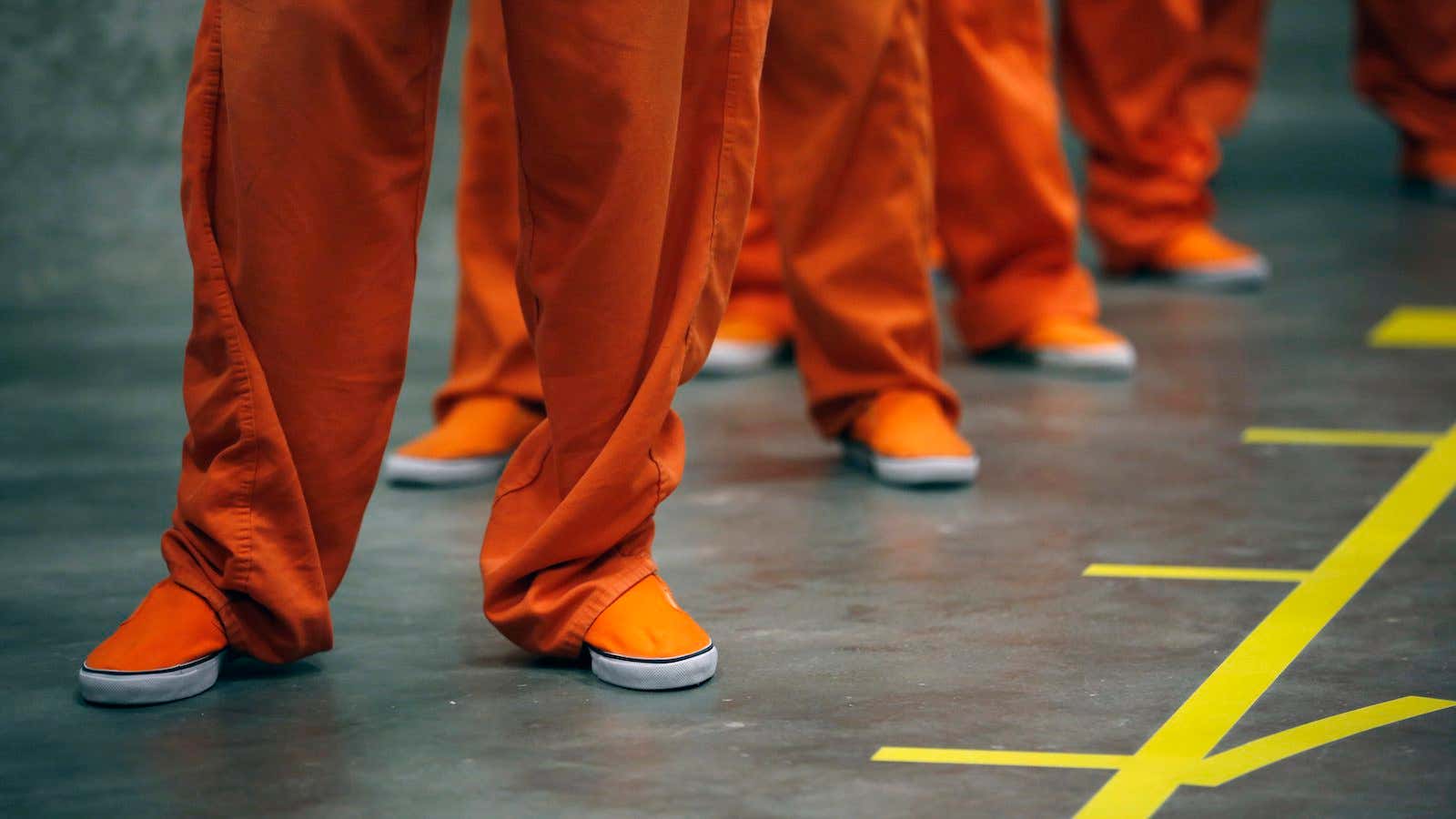 Prison inmates stand in line.