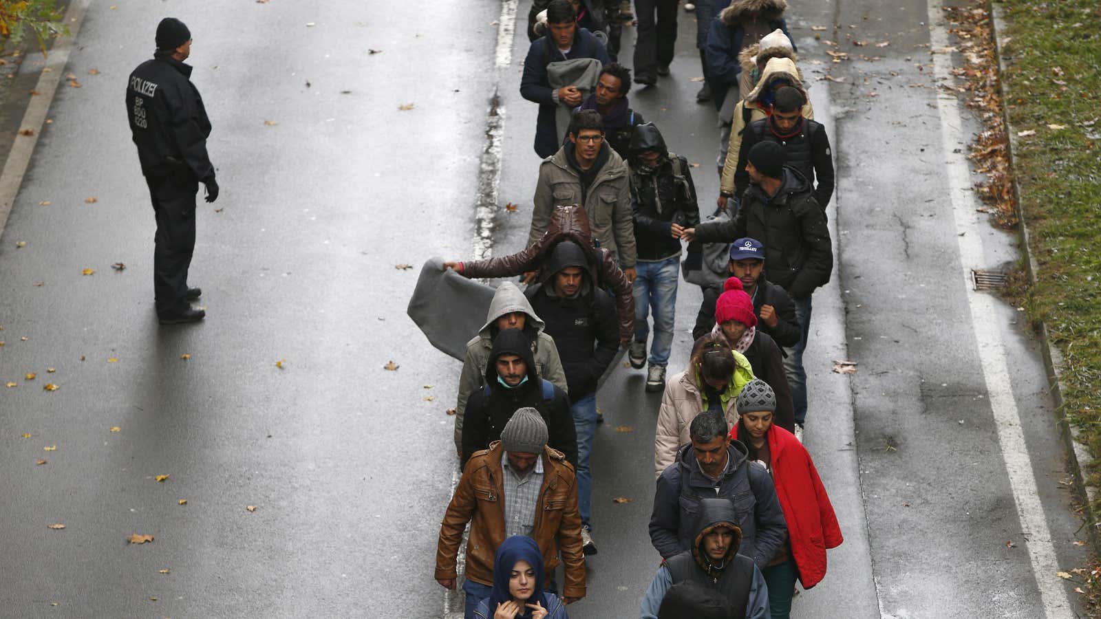 Migrants walk in the wet and cold along a street in the Austrian-German border region.