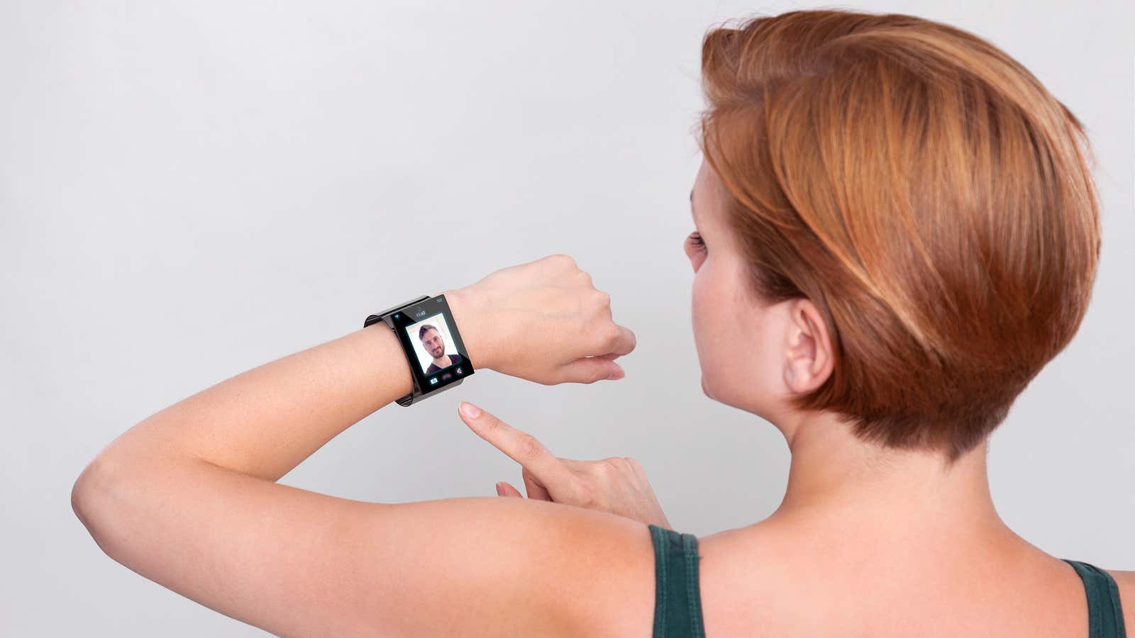 Girl with a modern Internet Smart Watch on grey background. On the screen you can see a videochat. All Texts, Icons, Computer Interfaces of the…