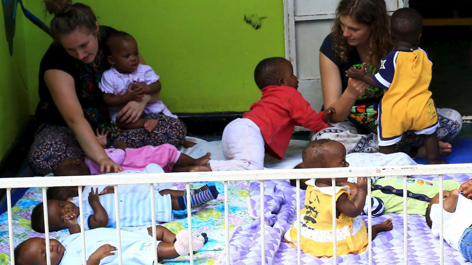 Local and foreign volunteers play with abandoned babies at children in Kampala .