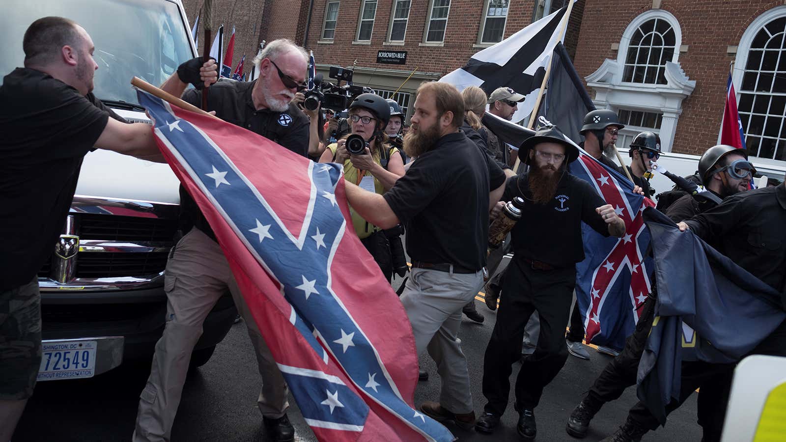 People struggle with a Confederate flag as a crowd of white nationalists are met by a group of counter-protesters in Charlottesville, Virginia, U.S., August 12, 2017.  REUTERS/Justin Ide – RTS1BIRV