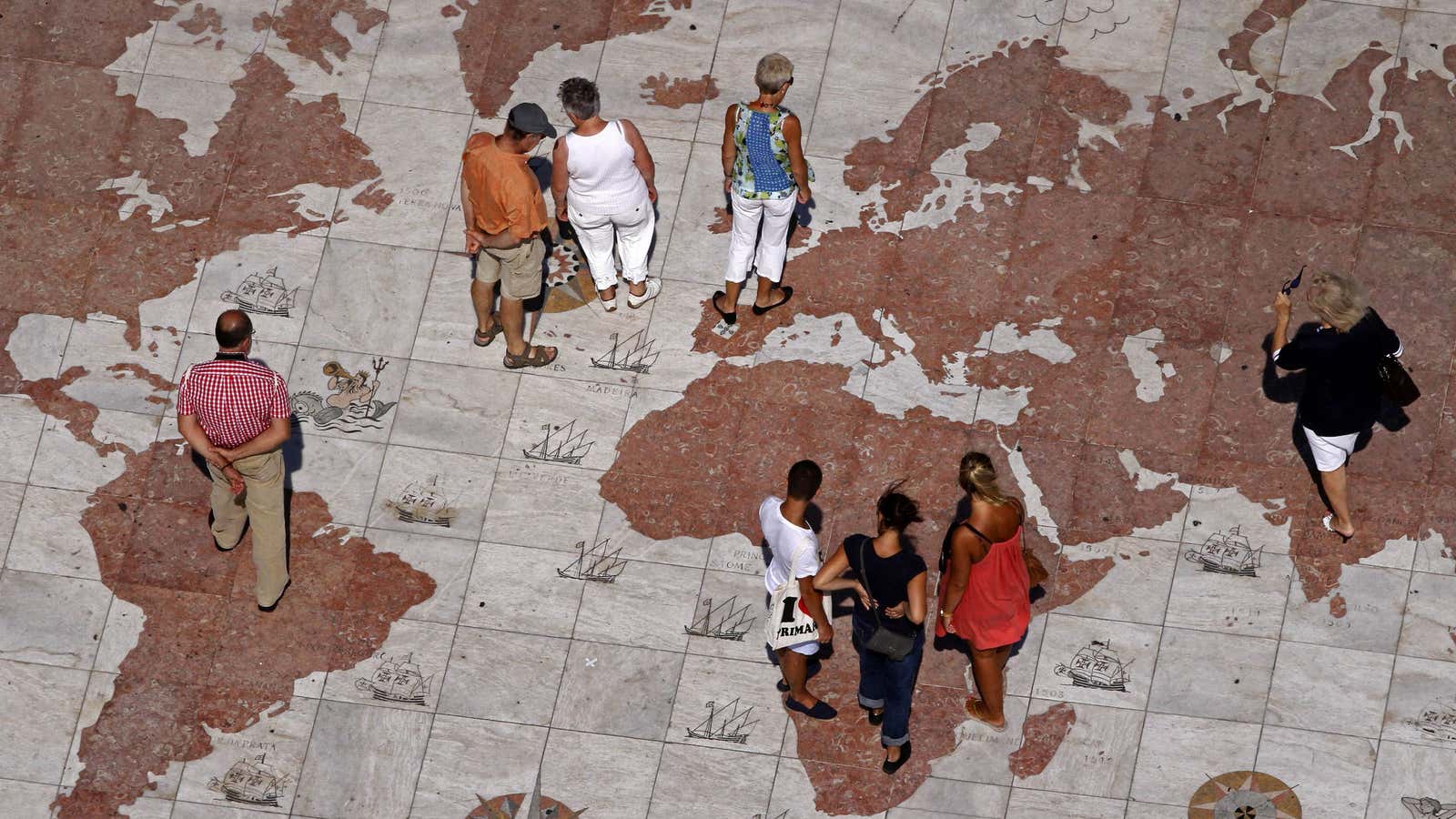 People walk over a world map engraved in marble in Lisbon September 14, 2011. Global markets have been roiled since the end of July by…