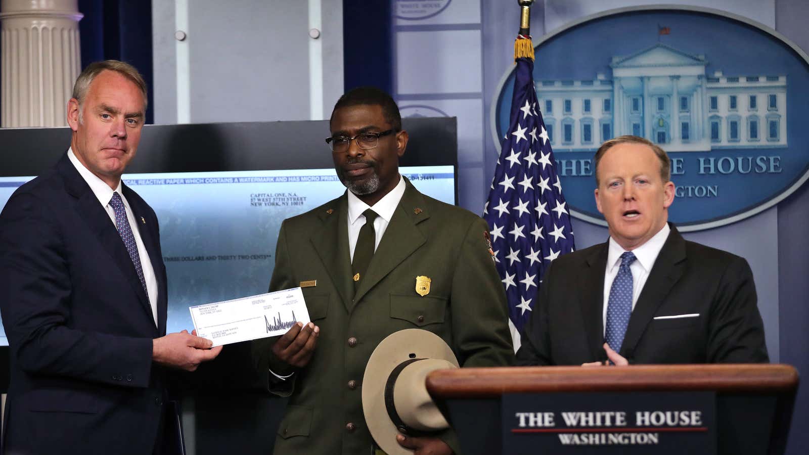 Interior secretary Ryan Zinke accepts Trump’s check at a White House press conference.