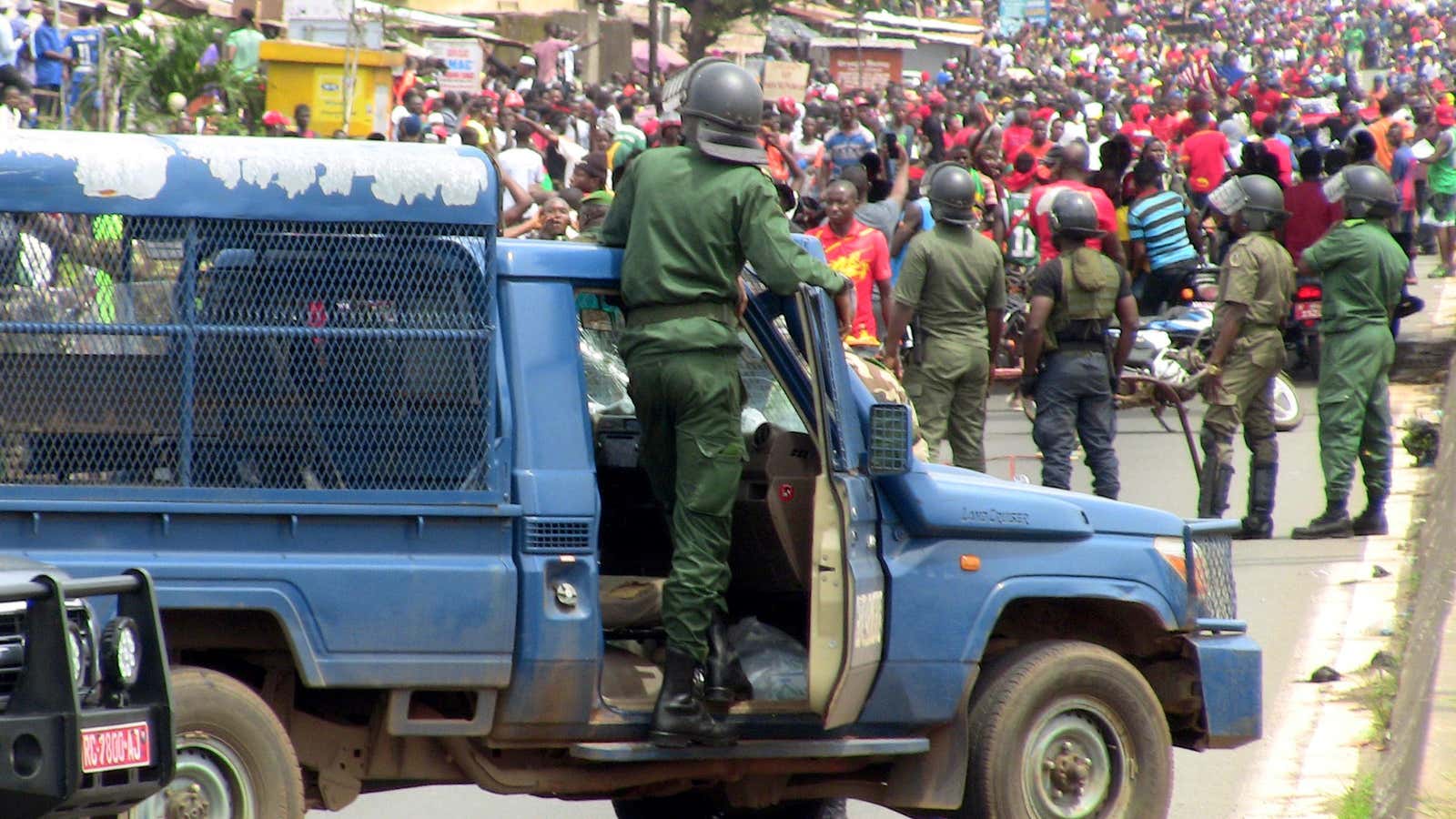 Members of security forces stand guard as people march during a protest over a suspected effort by president Alpha Conde to seek a third term in Conakry, Guinea Oct. 24, 2019.