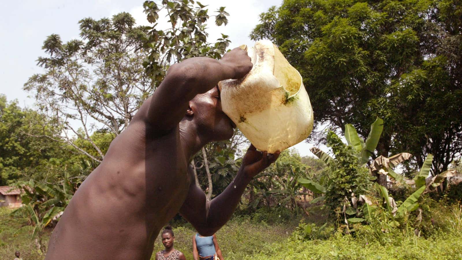 A man drinks water collected from a well, near Firestone rubber tree plantation on the edge of the Farmington River