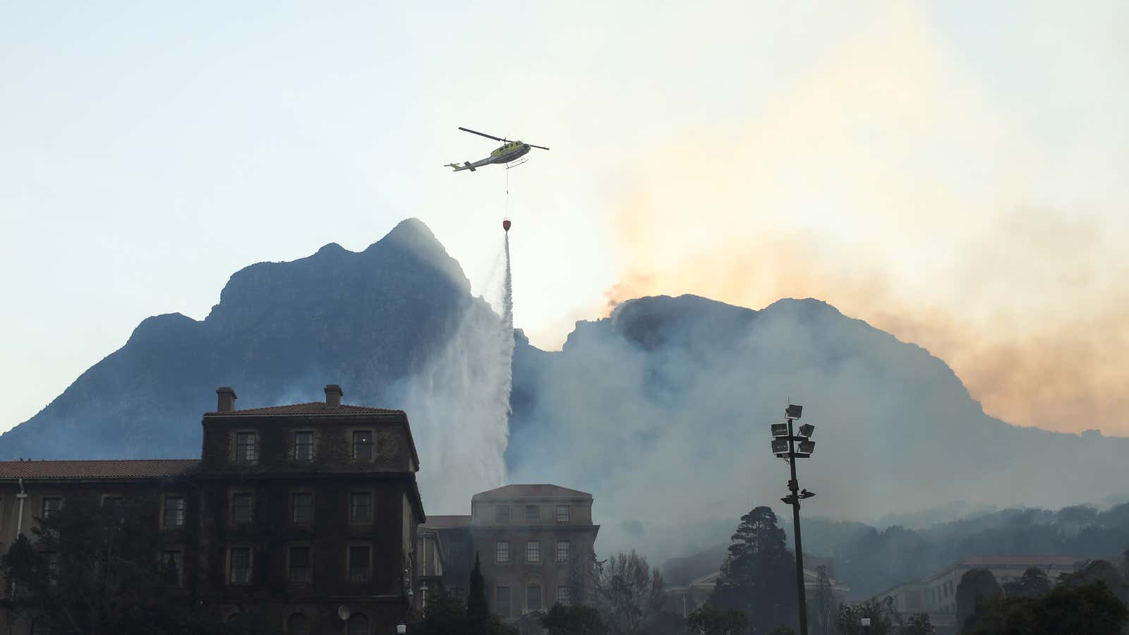 A helicopter drops water as the library at the University of Cape Town burns after a bushfire broke out on the slopes of Table Mountain in Cape Town on April 18.