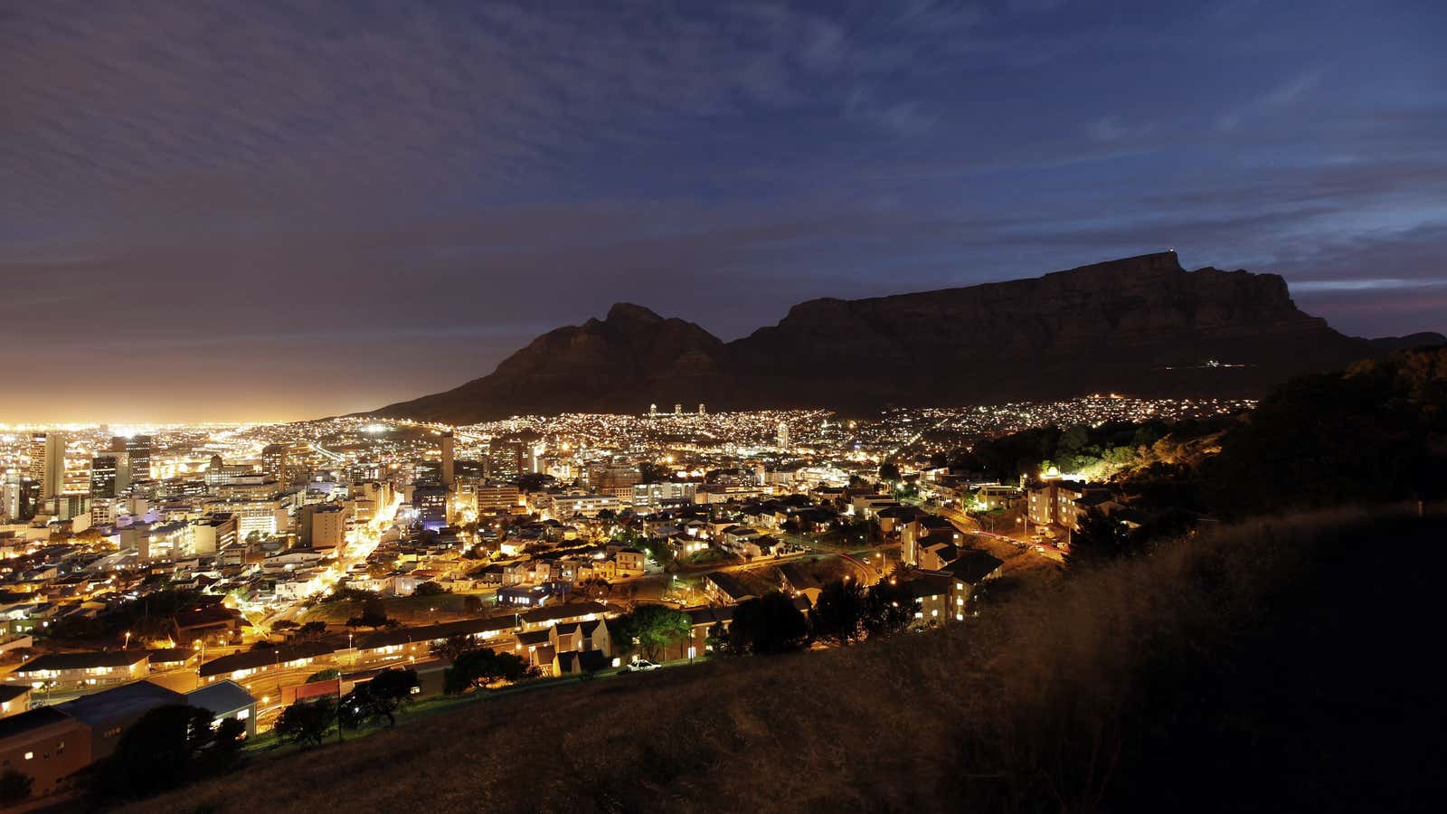 Cape Town lights up as dusk falls over the city’s backdrop Table Mountain, November 2, 2009. Cape Town is one of nine South African cities…