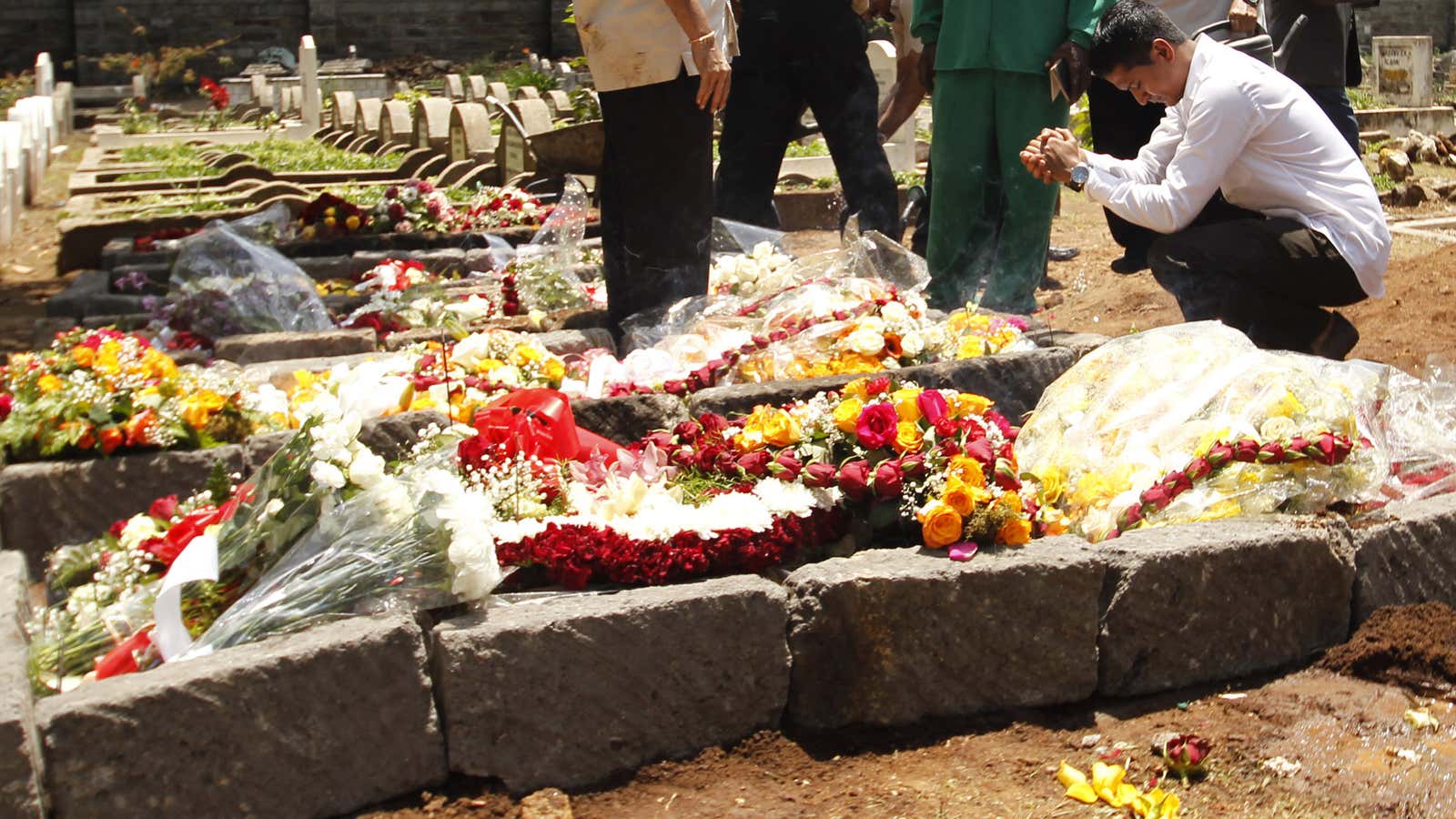 A relative kneels near the gravesite of Ruhila Sood, a Kenyan journalist who belonged to the tiny Ismaili Muslim community.