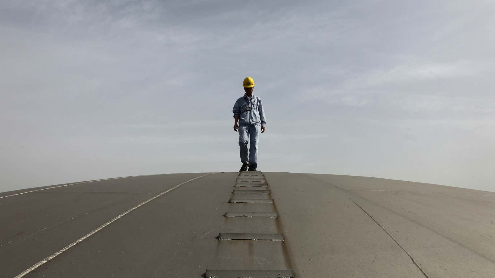 Worth more than it was. An oil worker walks on top of one of Sinopec’s giant oil tanks.