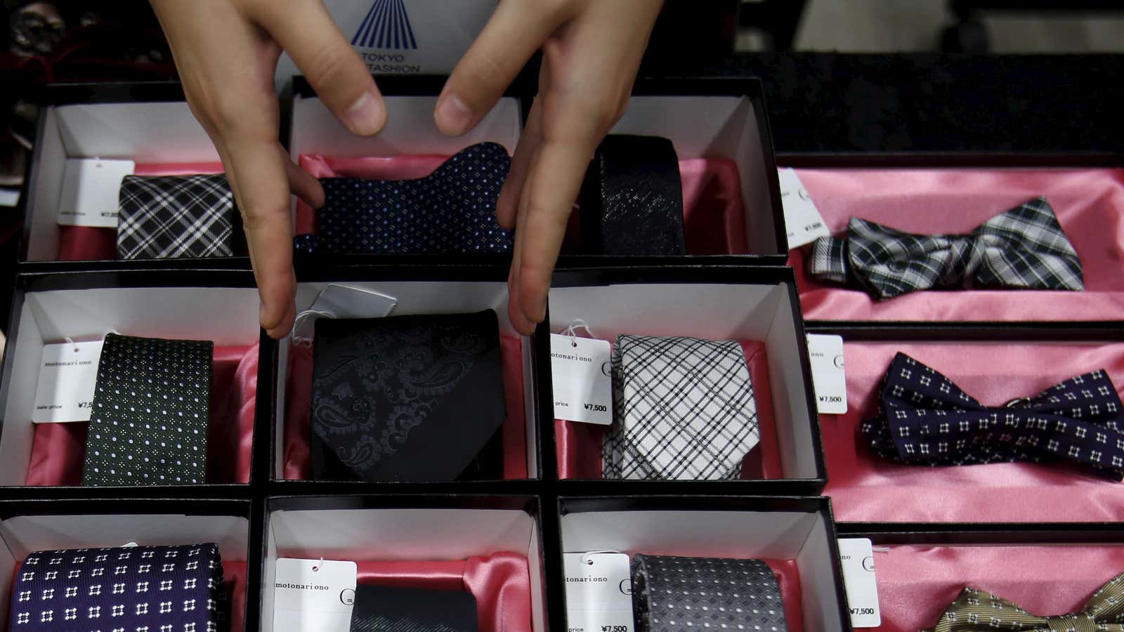 A shop clerk adjusts a tie displayed at an exhibition and sale during Tokyo Fantashion 2015 at a shopping district in Tokyo, Japan, August 16,…