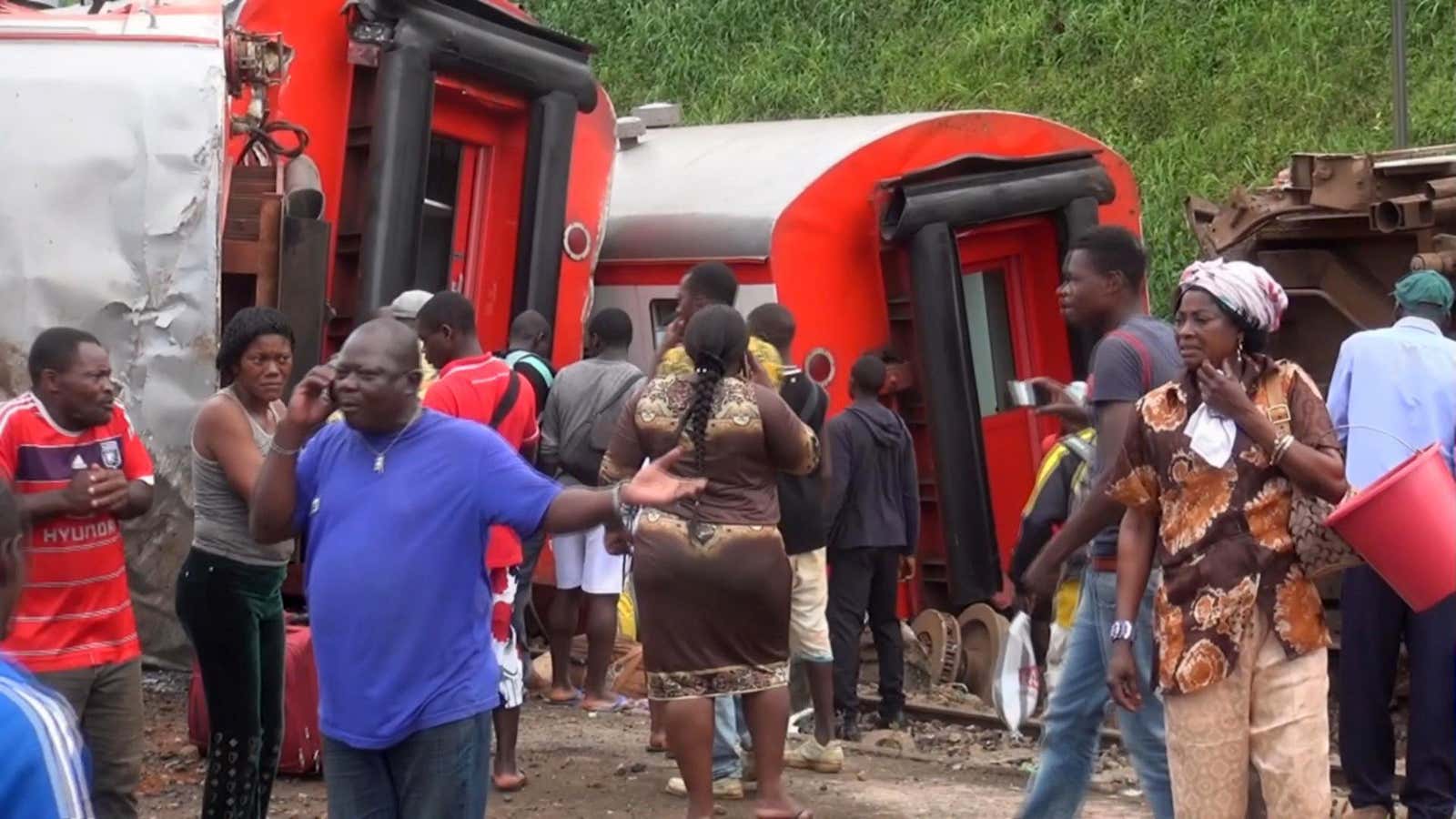 Passengers stand beside derailed train carriages after an accident in Eseka, Cameroon on Oct. 21.