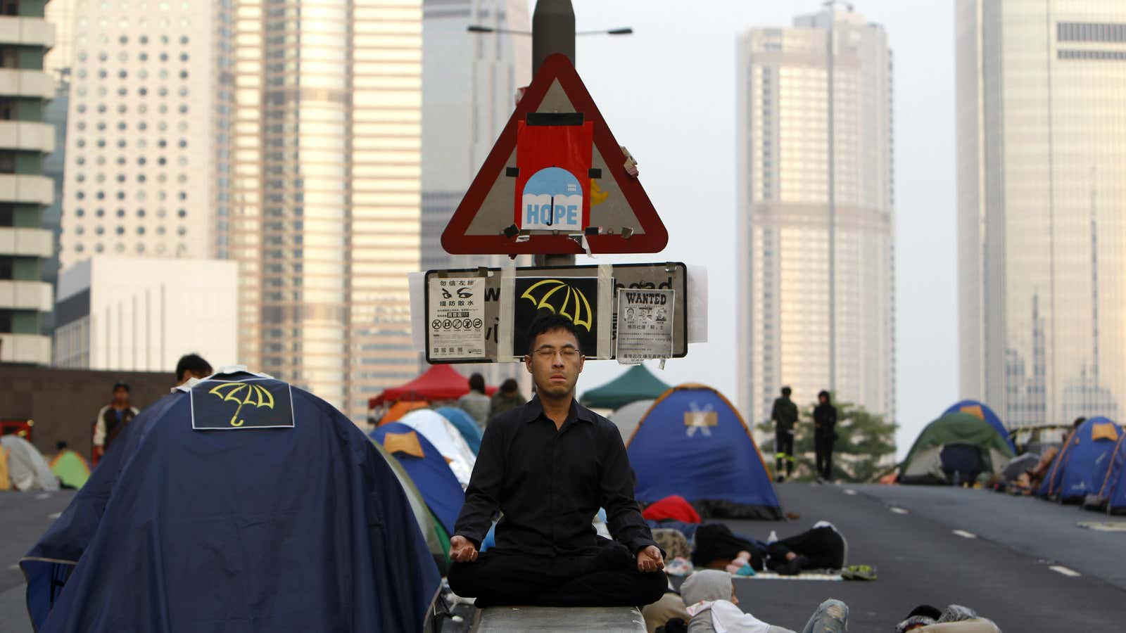 A pro-democracy protester meditates on a highway median.