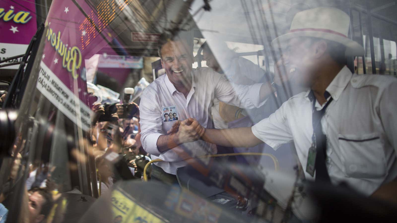 In this Tuesday, Sept. 30, 2014 photo, Aecio Neves, presidential candidate of the Brazilian Social Democracy Party, PSDB, greets a bus driver outside the “Mercadao…