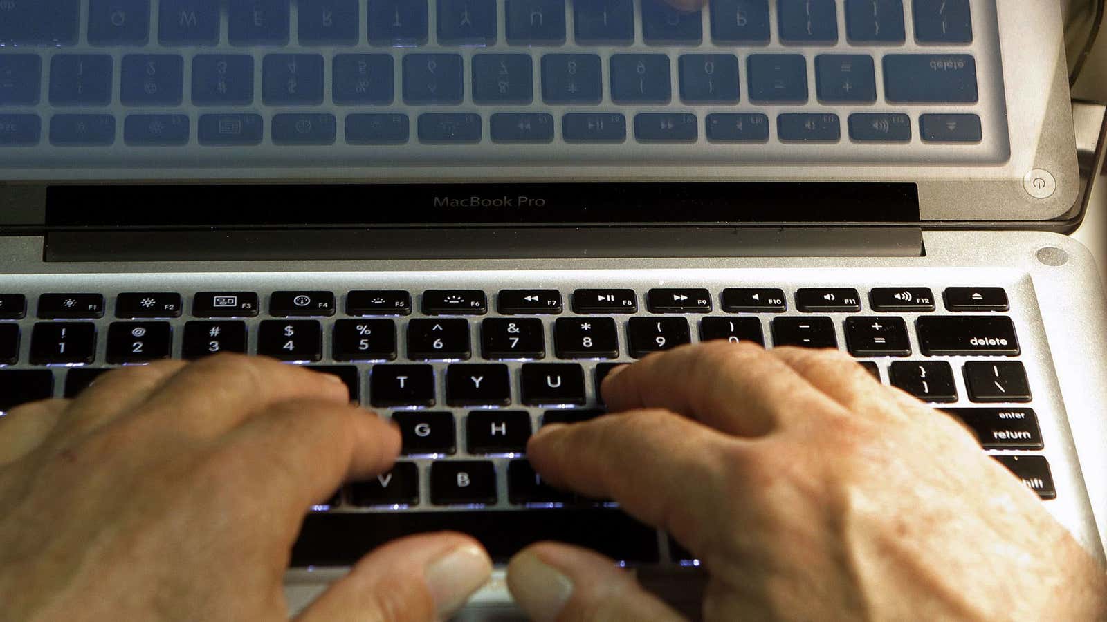 Hands type on a computer keyboard.