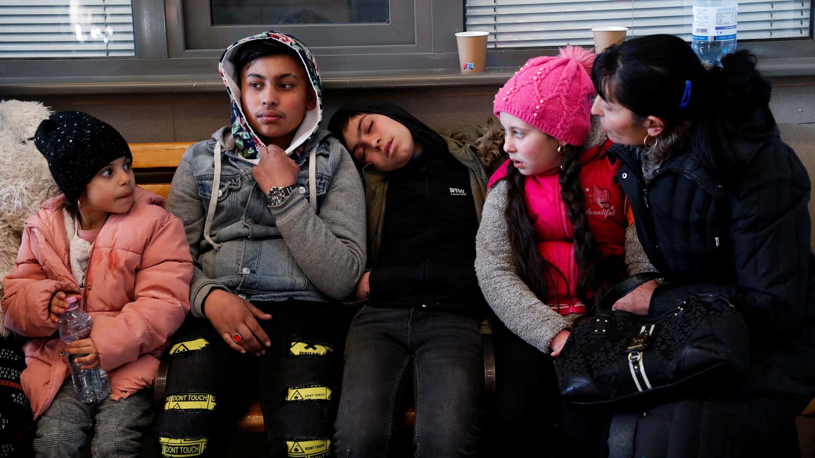 A woman watches over a group of children on a train station bench, after they arrive in Hungary from Ukraine.