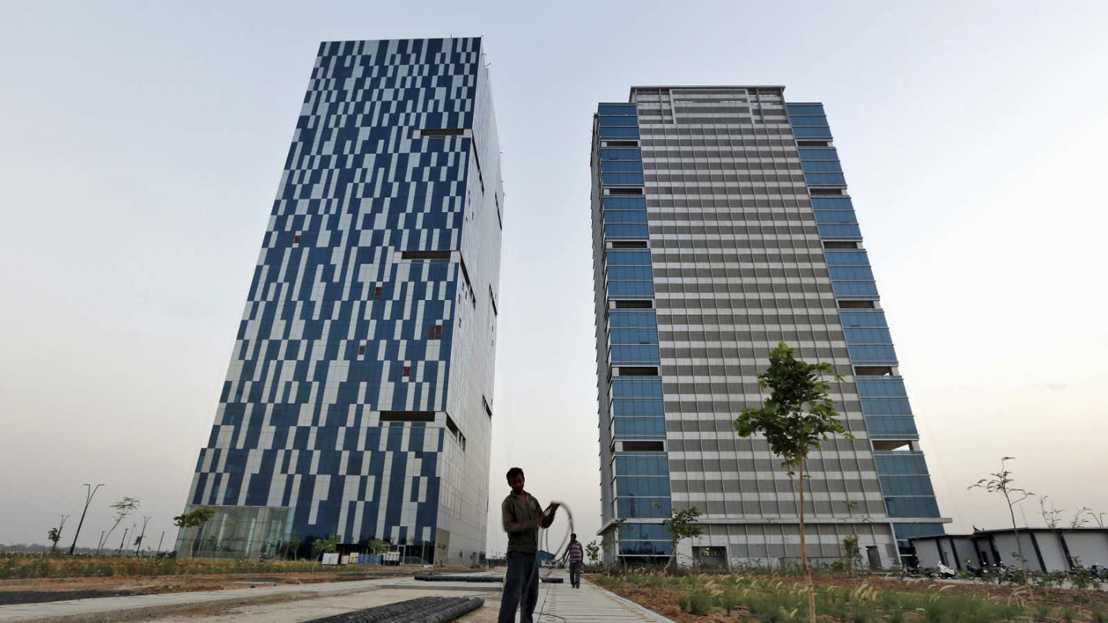 A worker folds the cable of a welding machine in front of two office buildings.