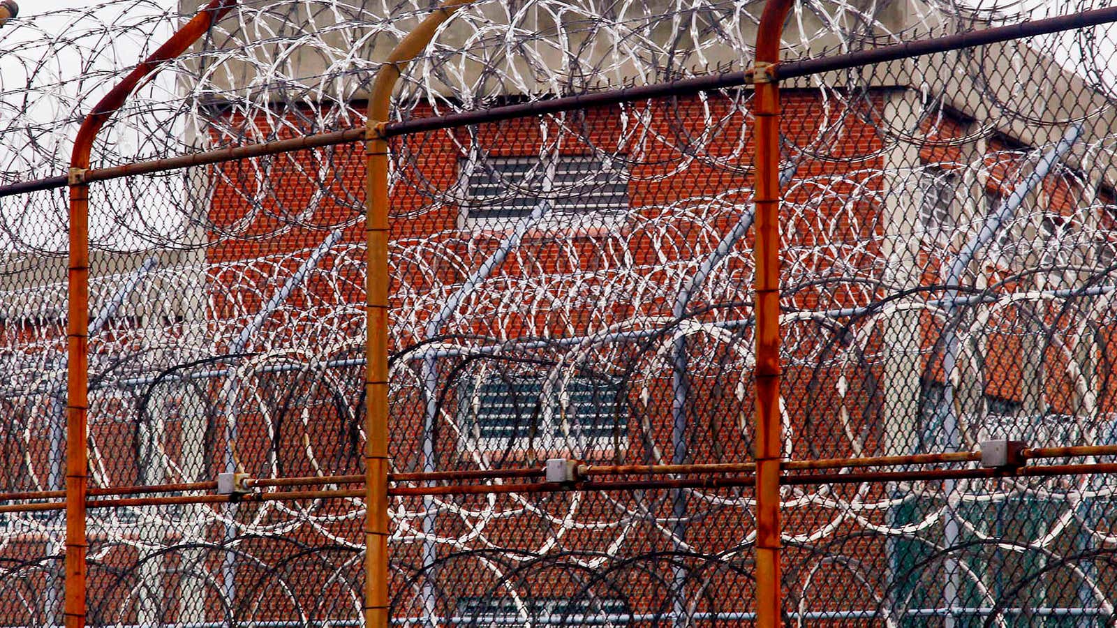 A fence covered in barbed wire surrounds inmate housing at the Rikers Island.