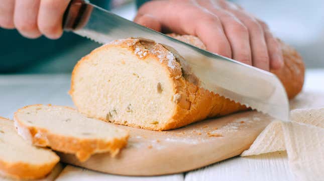 A person slicing bread with a bread knife.