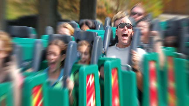 A man screams while riding a roller coaster filled with other people. 