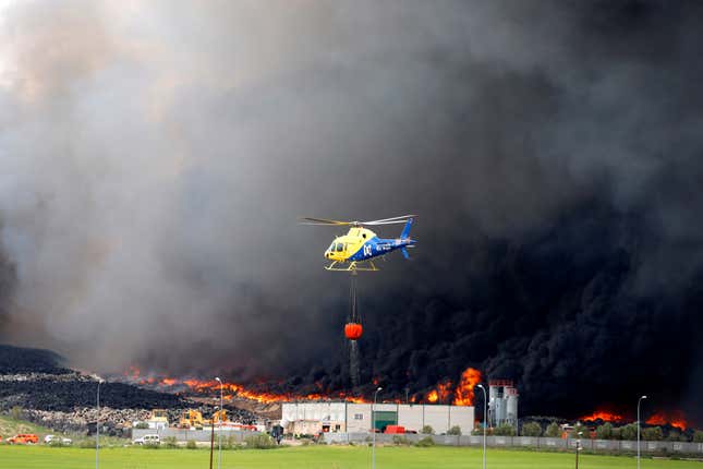 A helicopter prepares to throws water over the fire.