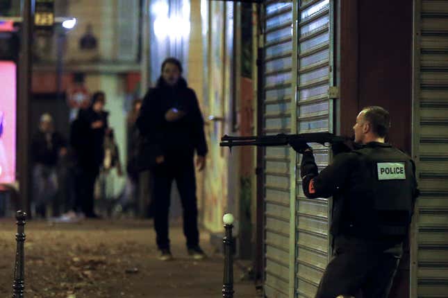 A French police officer takes cover while on the lookout for the shooters who attacked the restaurant Le Petit Cambodge.