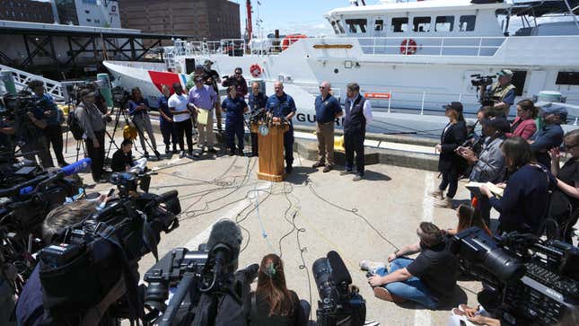 U.S. Coast Guard Capt. Jamie Frederick, center at microphone, faces reporters during a news conference, Wednesday, June 21, 2023, at Coast Guard Base Boston, in Boston. The U.S. Coast Guard says sounds and banging noises have been heard from the search area for Titanic submersible. 
