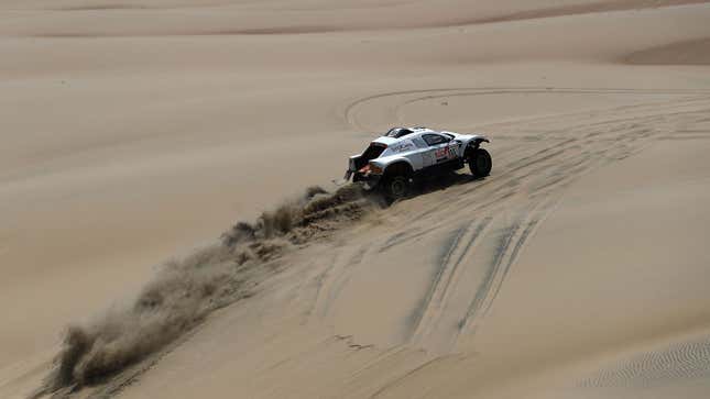 The white Sodicars rally truck driving across a sand dune 
