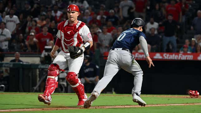 Mariners’ Sam Haggerty runs by  Angels ‘catcher Max Stassi and heads for home plate in the ninth inning against the Angels.