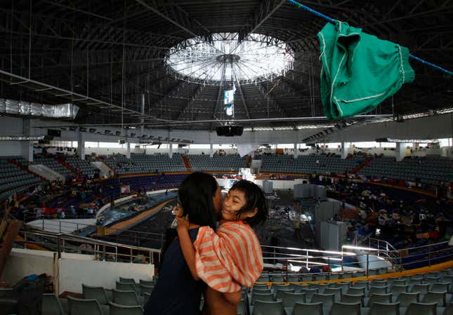 A woman helps her daughter dry herself after she took a bath inside the Tacloban City Convention Centre, also known as the "Astrodome", where she and her family is temporarily staying, in Tacloban November 14, 2013. Philippine President Benigno Aquino was under growing pressure on Thursday to speed up the distribution of food, water and medicine to desperate survivors of a powerful typhoon and to revive paralysed local governments.