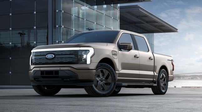A beige 2023 Ford F-150 Lightning is parked in front of a glass building.