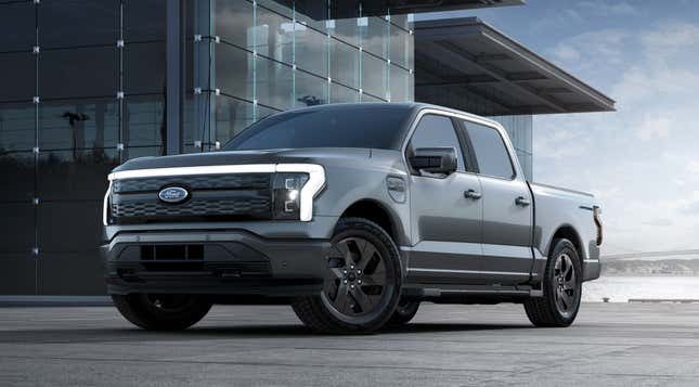 A gray 2023 Ford F-150 Lightning is parked in front of a glass building.