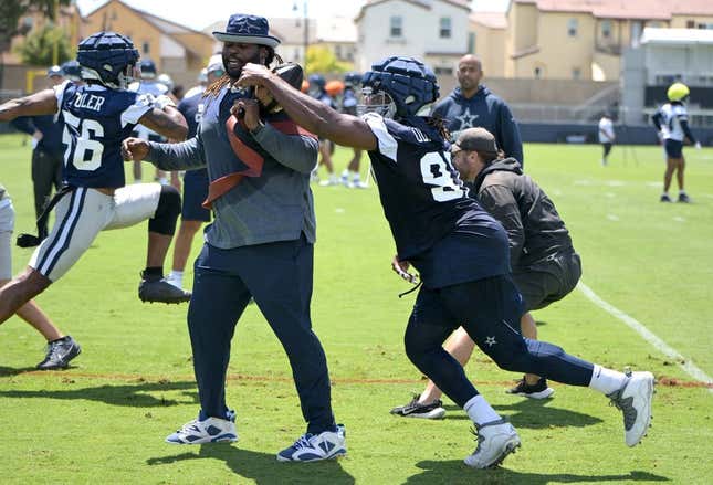 Jul 26, 2023; Oxnard, CA, USA;  Dallas Cowboys defensive end DeMarcus Lawrence (90) reaches around assistant defensive line coach Sharrif Floyd during training camp drills at River Ridge Playing Fields in Oxnard, CA.